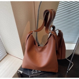 Detail of brown litchi pattern leather bag with adjustable strap and silver buckle