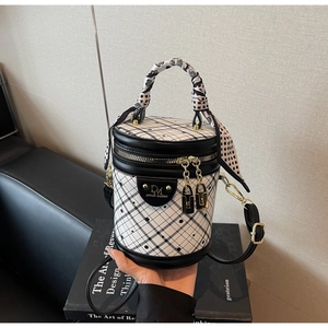 Detail of checkered cylinder bucket bag with silk scarf handle and gold zipper