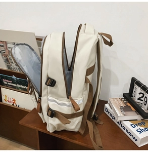 Detail of multi-compartment interior and side pocket with reflective strip on ivory backpack