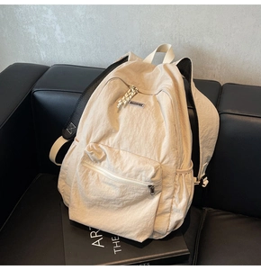 Detailed close-up of beige nylon backpack fabric and front zipper pocket on a sofa