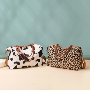 Detail view of large travel bags in cow and leopard prints with brown straps