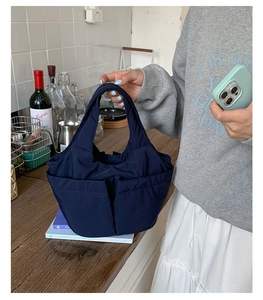 Detail of navy blue multi-pocket nylon tote bag featuring durable stitching and handles
