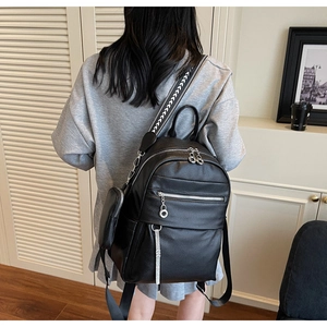 Detail of black pebbled leather backpack with woven strap and mini coin pouch hanging