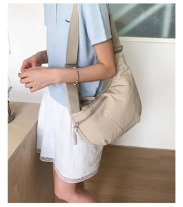 Detail of light khaki crescent hobo bag with wide shoulder strap and woven zipper puller