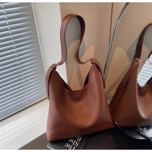 Detail of caramel brown litchi leather texture and silver buckle on hobo bag