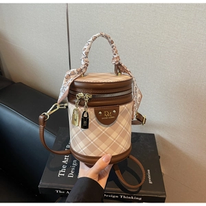 Detail of beige and brown bucket bag with silk scarf handle and metal lock pendants