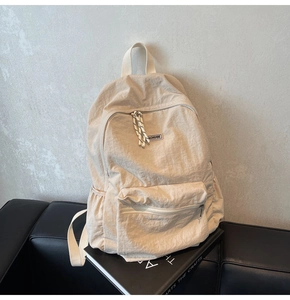 Close-up detail of off-white nylon backpack featuring multiple zip pockets and a minimalist design