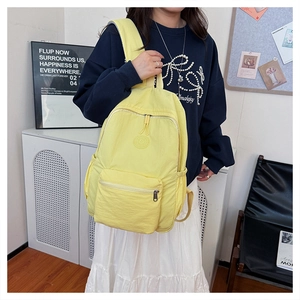 Vue détaillée d'un sac à dos en nylon jaune avec logo rond et poche latérale