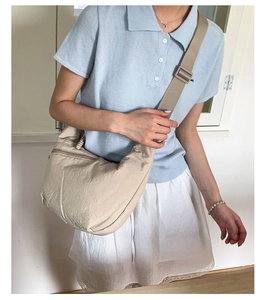 Detail view of beige nylon crescent crossbody bag with adjustable wide strap and front zipper