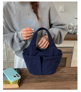 Detail of navy blue quilted nylon bucket bag with dual front pockets and top handle