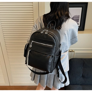 Close-up of black leather backpack with lychee texture and silver tassels on a model