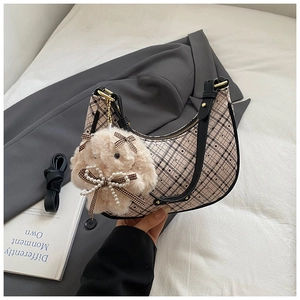 Detail of beige plaid crescent bag with black strap and plush rabbit pearl charm