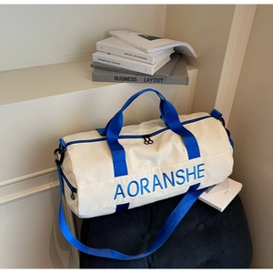Detail of travel duffle bag featuring blue nylon handles and adjustable shoulder strap