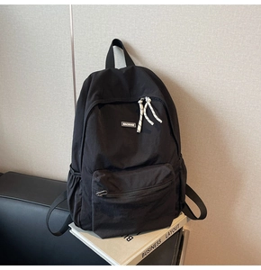 Detail view of durable black nylon backpack featuring woven rope zippers and side pockets