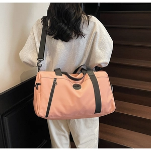 Pink large capacity travel bag worn by a model in a cozy indoor wooden staircase setting