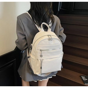 Detail of white lychee texture backpack with silver zippers worn by a model in casual suit