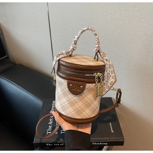 Detail of checkered bucket bag with leather trim and decorative heart print scarf handle
