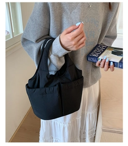 Close-up of black canvas tote bag with functional exterior pockets for daily storage
