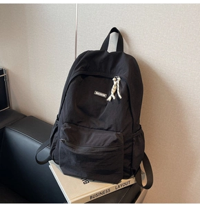 Close-up of black nylon backpack featuring brand logo and woven zipper pullers