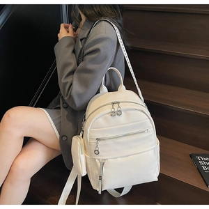 Detail view of a white PU leather backpack with a round coin purse on a model