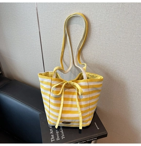 Detail of yellow and white striped canvas tote bag with a decorative bow on a book