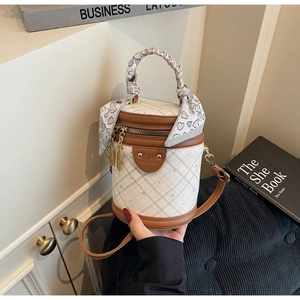 Detail of white quilted bucket bag with brown leather trim and silk scarf wrapped handle