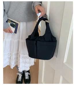 Detail of minimalist black nylon bucket bag with multi-pockets and stylish wide strap