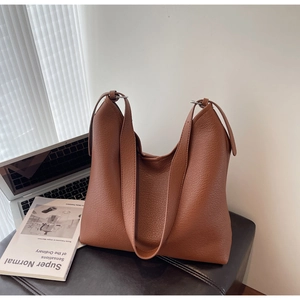 Detail of premium brown pebble leather texture and metal rings on a commuter tote bag