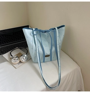 Detail of light blue polka dot tote bag with long strap and handmade label decoration