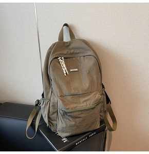 Close-up of military green nylon backpack featuring branded label and woven zipper pulls