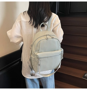 Detail view of light green backpack with lychee texture leather and ring puller zipper