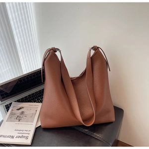 Brown lychee grain leather hobo shoulder bag shown in a modern lifestyle desktop setting