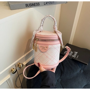 Detail view of pink plaid barrel bag featuring decorative silk scarf and metal brand logo