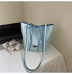 Close-up of light blue polka dot tote bag with bow closure and Handmade metal tag
