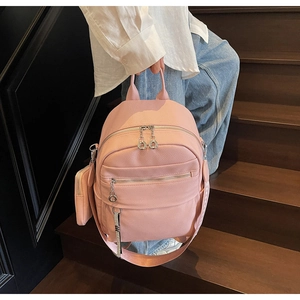 Detail of pink litchi grain leather backpack with multiple pockets and mini coin purse