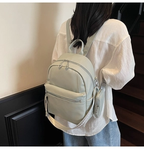 Close-up of mint green pebble leather backpack with decorative leaf patterned woven strap
