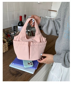 Detail of pink quilted puffer handbag with two front pockets and nylon texture finish