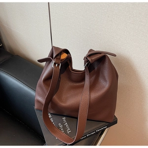 Close-up of dark brown lychee texture leather shoulder bag on a vintage sofa