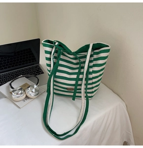 Close-up of green and white striped canvas tote bag with drawstring and handmade leather label