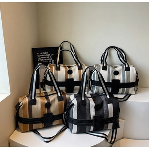 Detail of striped travel bags in caramel, gray, yellow and black with adjustable straps