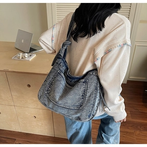 Detail of vintage washed denim tote bag with functional double front pockets and knotted strap