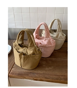 Detailed close-up of multi-pocket solid color nylon tote bags on a wooden surface