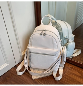 Detail of off-white pebble leather backpack with woven strap and mini coin purse charm