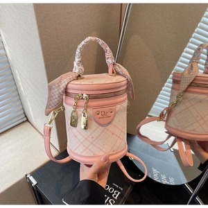 Detail of pink quilted cylindrical bucket bag with silk scarf handle and gold hardware
