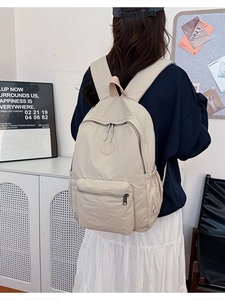 Sac à dos en nylon beige minimaliste avec plusieurs poches porté par un mannequin