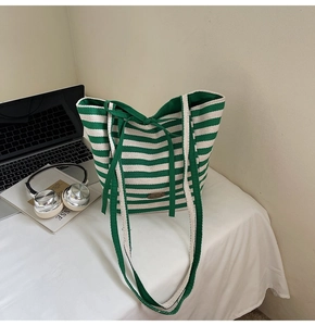 Detail of green and white striped canvas tote bag with brown handmade leather patch