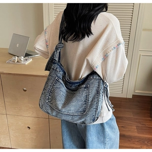 Detail showing the knotted shoulder strap and vintage washed denim texture on tote bag