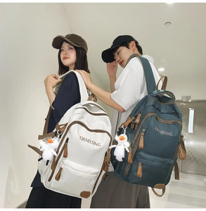 Detail view of large nylon backpacks in white and dark green with cute duck charms