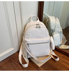 Detail of white lychee leather backpack with a mini coin pouch and patterned strap