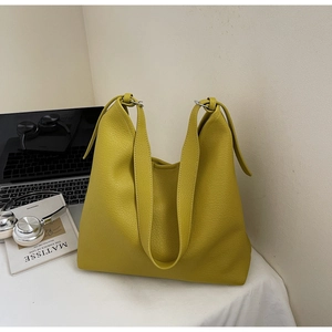 Detailed shot of yellow pebbled leather tote bag with wide strap and metallic rings